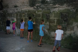 The kids look out the holes in the stones made for artillery.