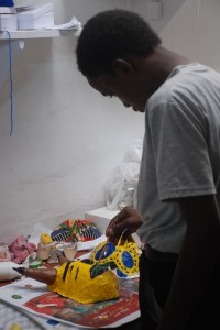 a student paints masks for Carnival